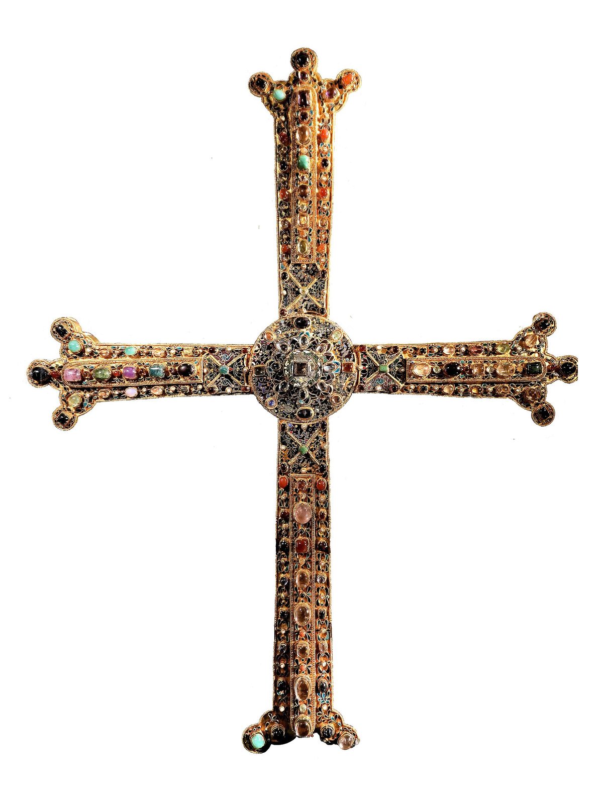 A tall jewelled cross covered in gold filigree and set stones, its arms ending in rounded terminals, against a white ground.
