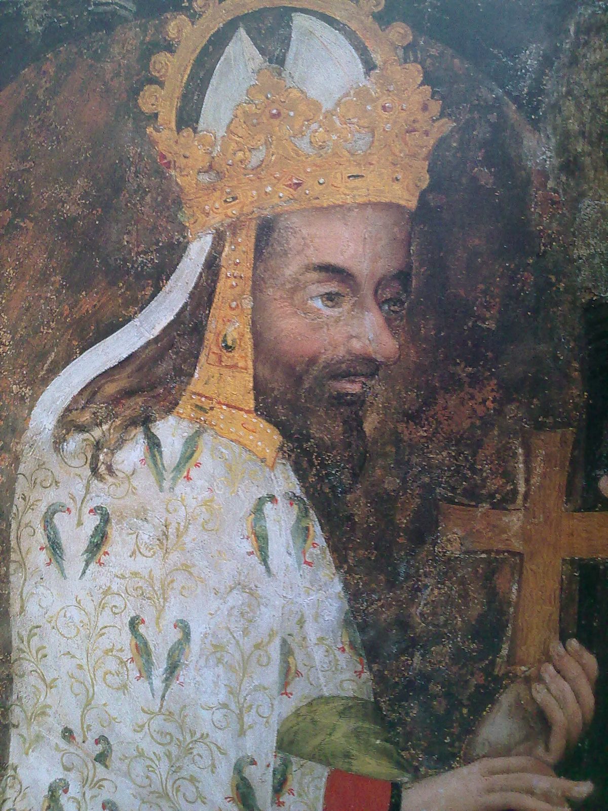 A wall painting of a bearded king in a crown holding a gold cross.
