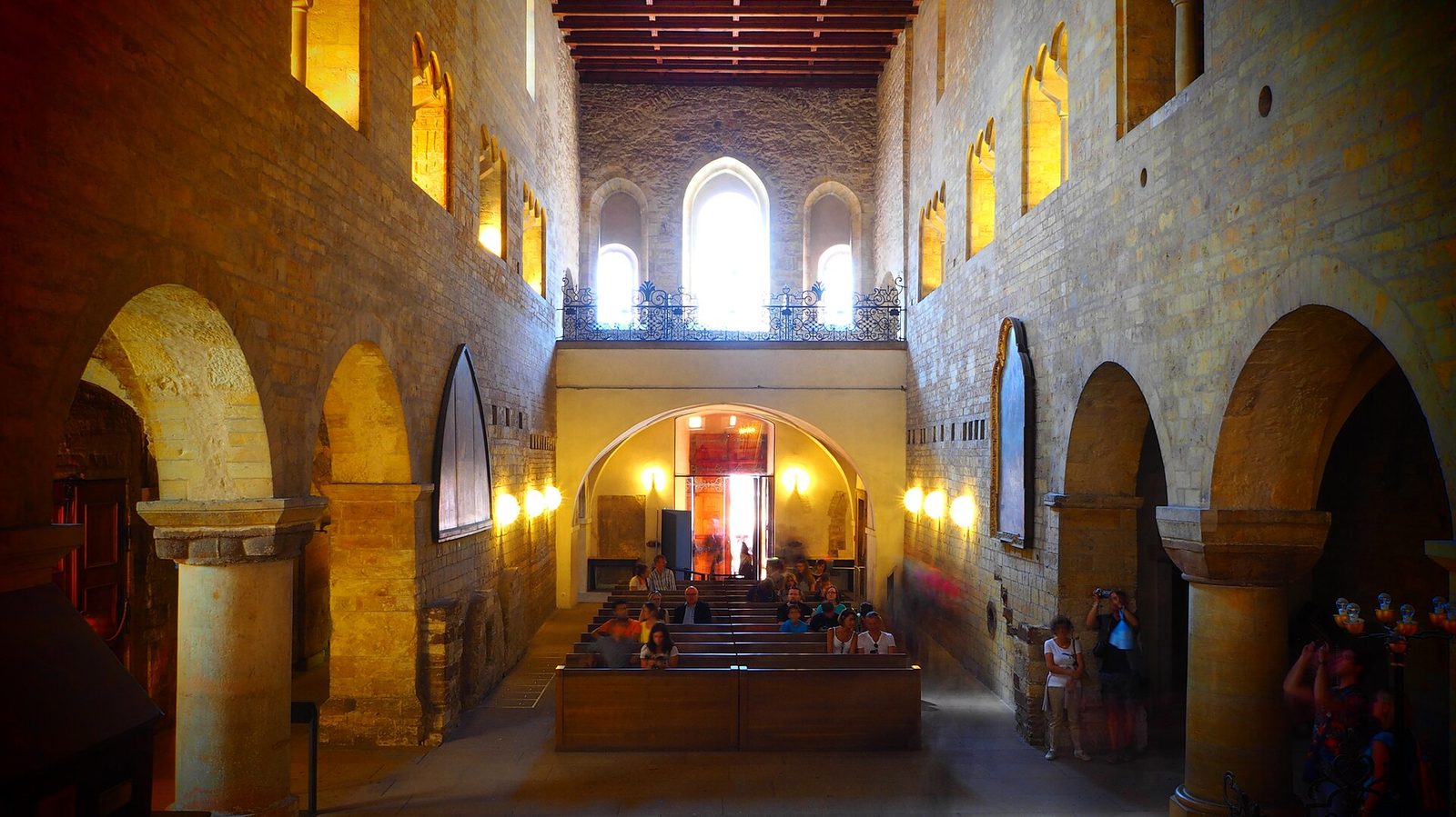The bare Romanesque nave of a church with round arches and a raised choir.