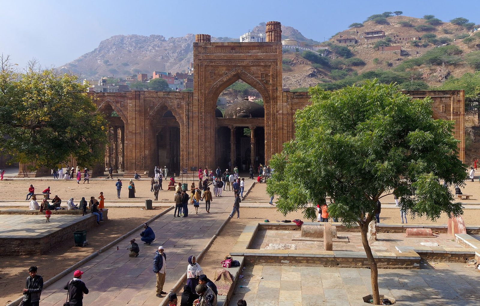 A ruined mosque screen of tall pointed arches in front of colonnades.