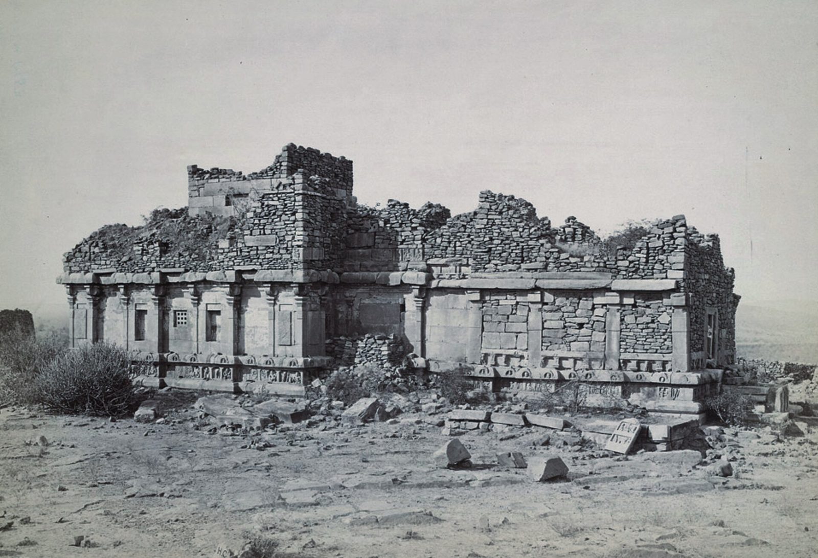 An old photograph of a ruined flat-roofed stone temple on a rocky hill.