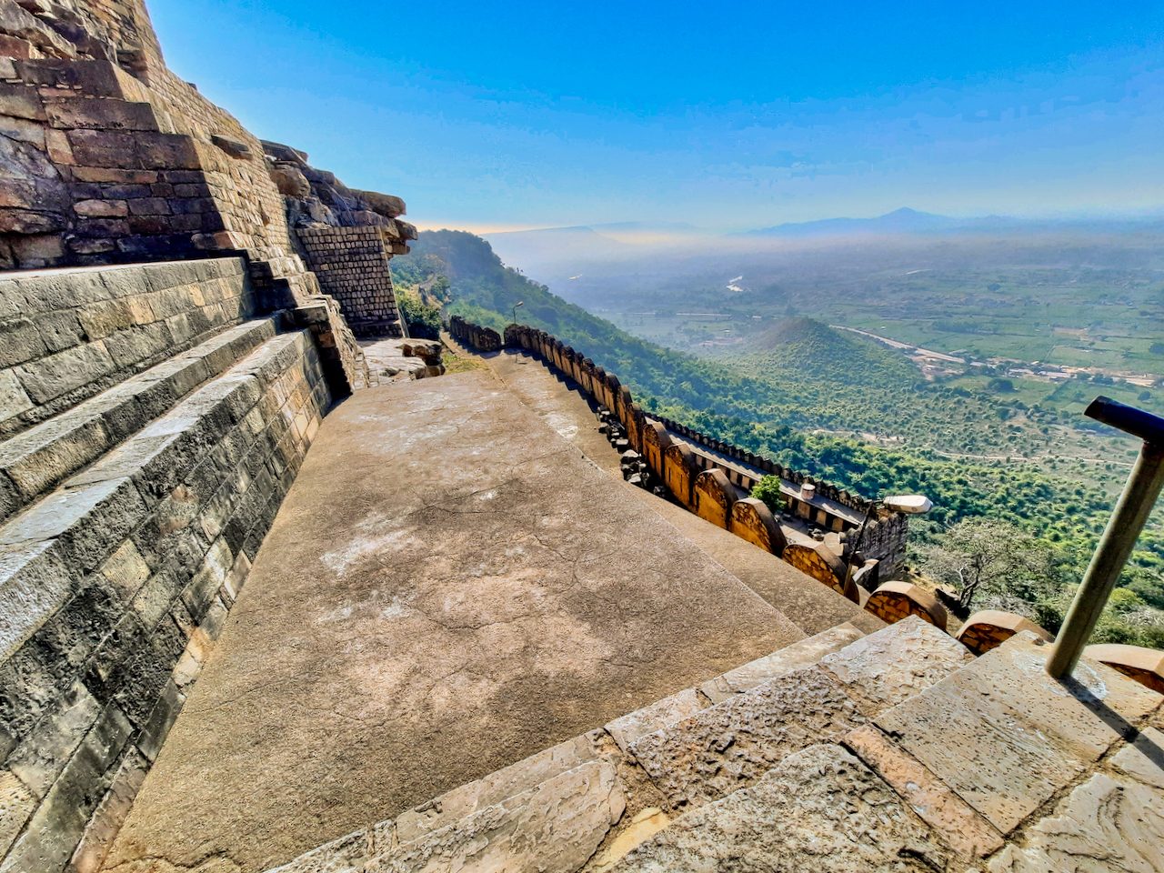 A stone stairway on a fortified hilltop looking out over wooded plains below.