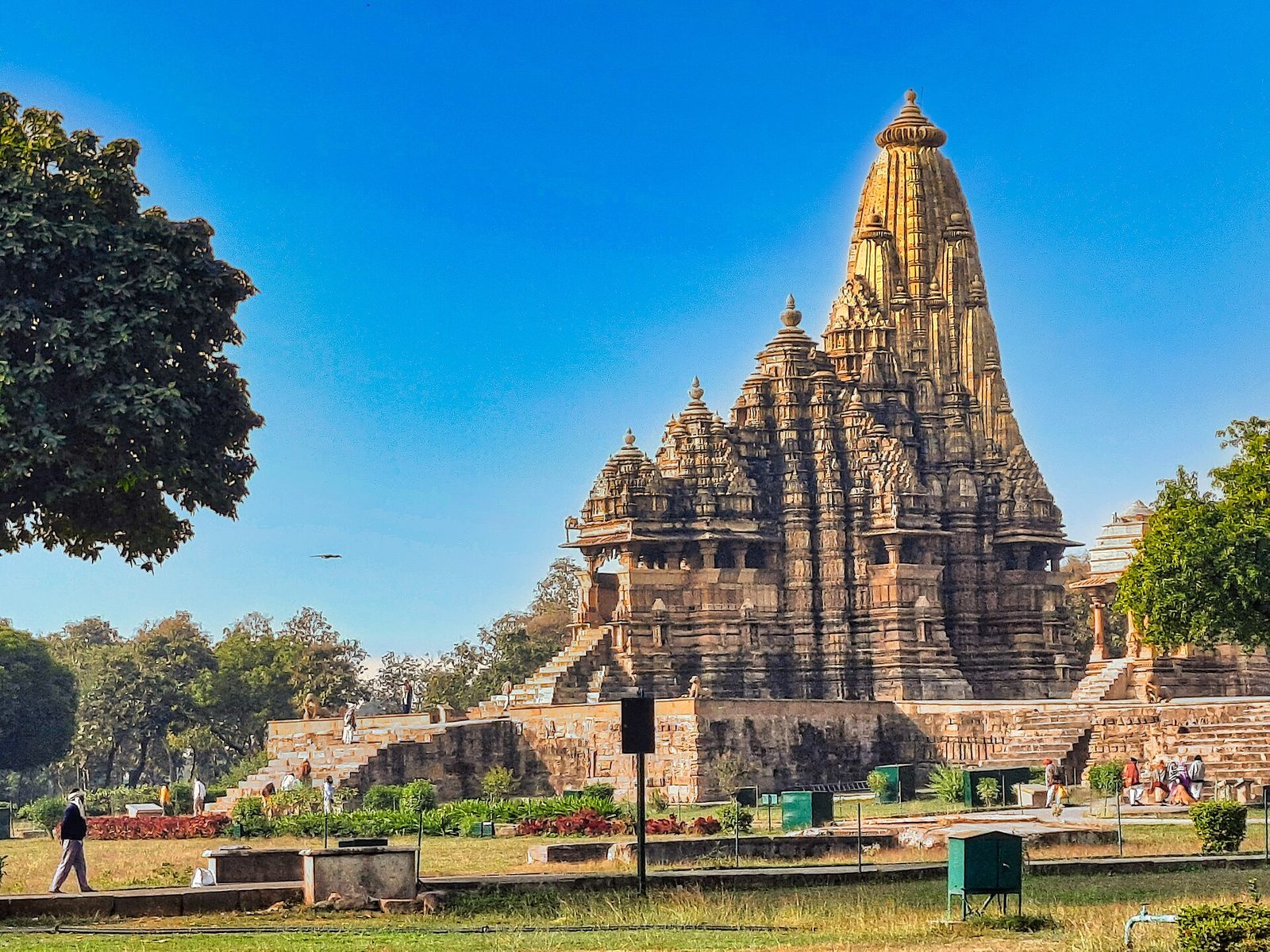 A towering sandstone temple with a tall central spire on a high platform.
