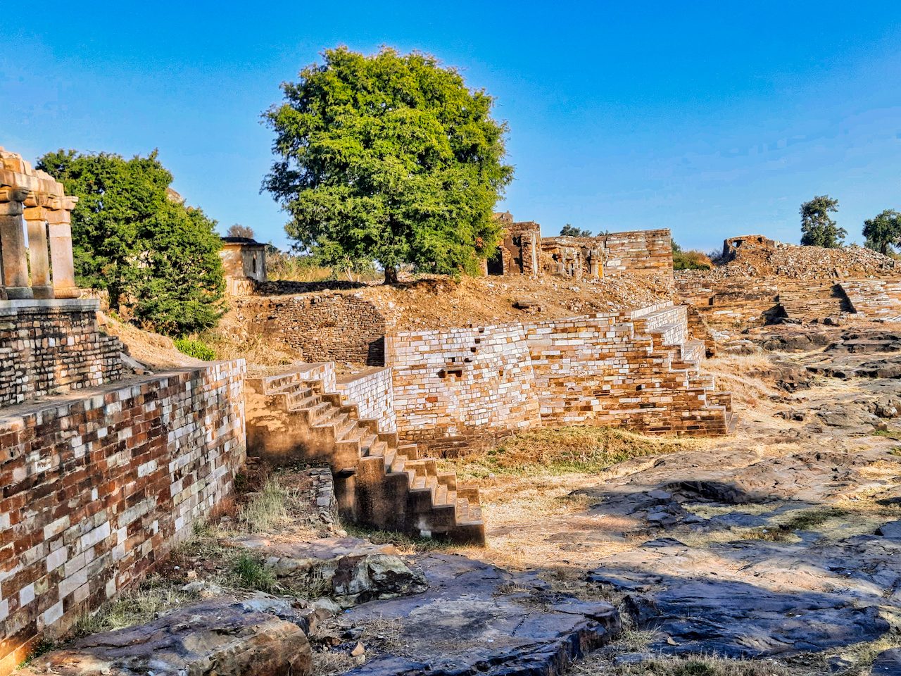 A large stone-lined reservoir with steps and ruined structures inside a fort.