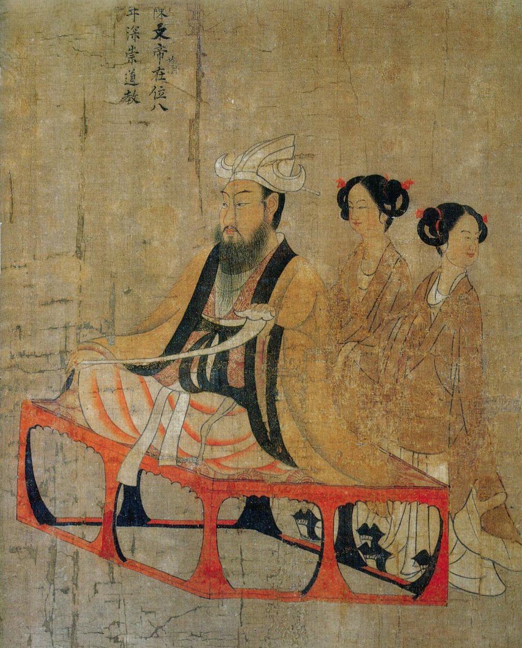 A painted bearded ruler in a white headcloth seated on a red litter, with two women behind him.