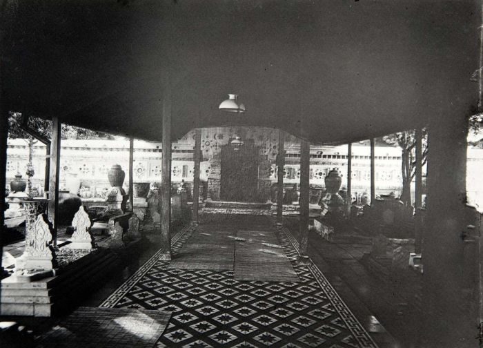 An old photograph inside a tomb complex: a long covered passage with a patterned tiled floor, its walls set with rows of inlaid porcelain plates.
