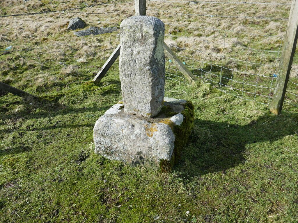 The worn stump of a stone cross shaft set in a block base on moorland.