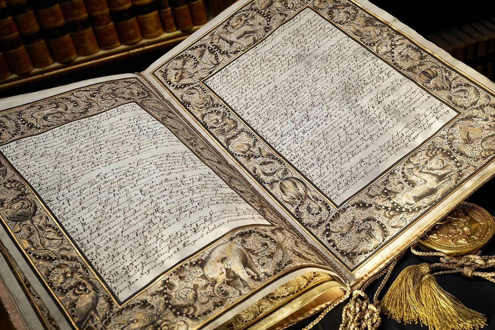 An open book bound in silver-gilt, its pages of fine handwriting framed by ornate metalwork.