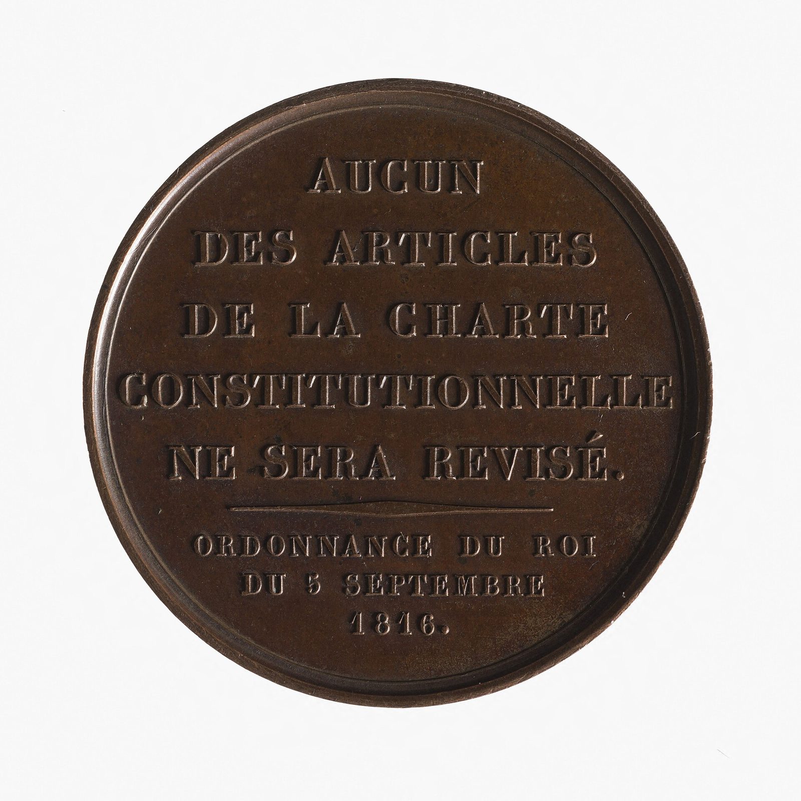 A bronze medal struck with six lines of raised capital lettering and no image, reading that no article of the constitutional Charter shall be revised, by royal ordinance of 5 September 1816.