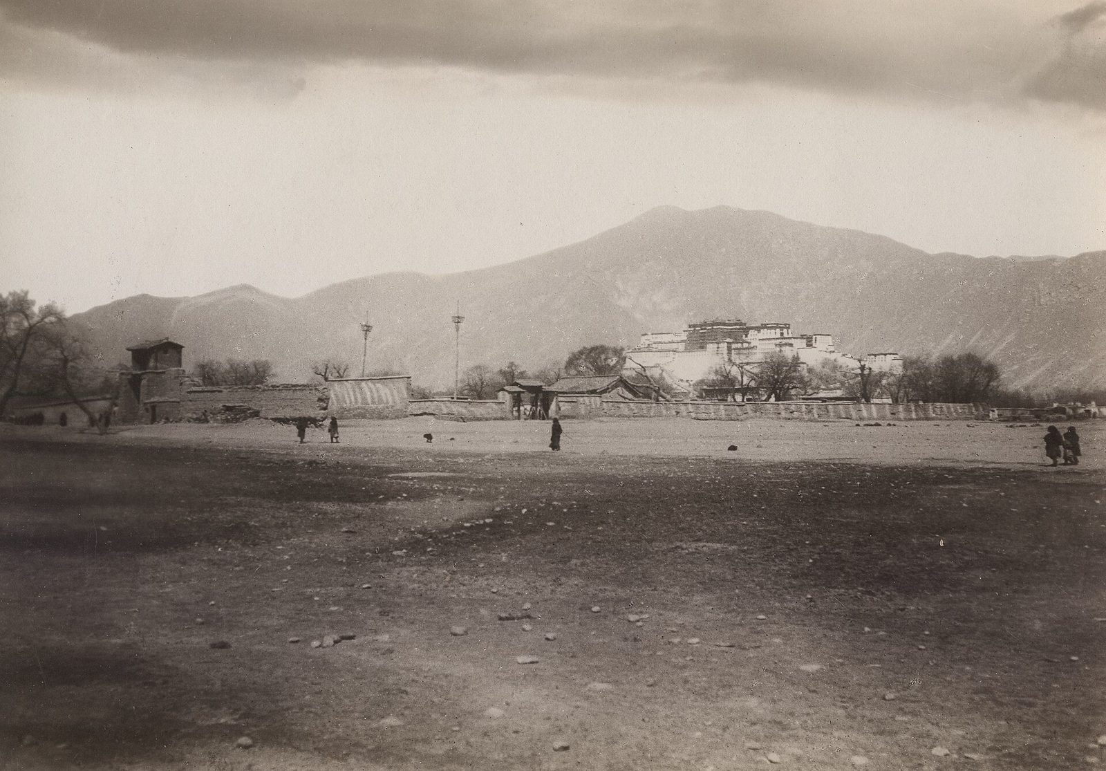 A sepia photograph of a wide plain with low buildings, the Potala on its hill in the distance.