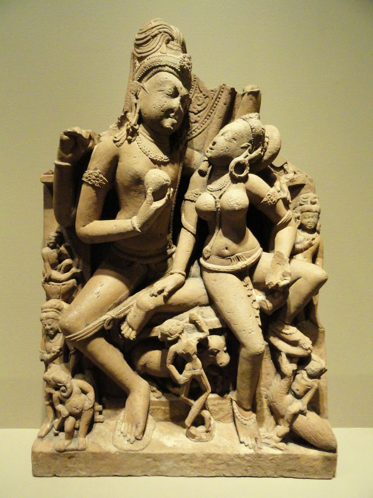 A sandstone relief of Shiva and Parvati seated together, with small attendant figures.