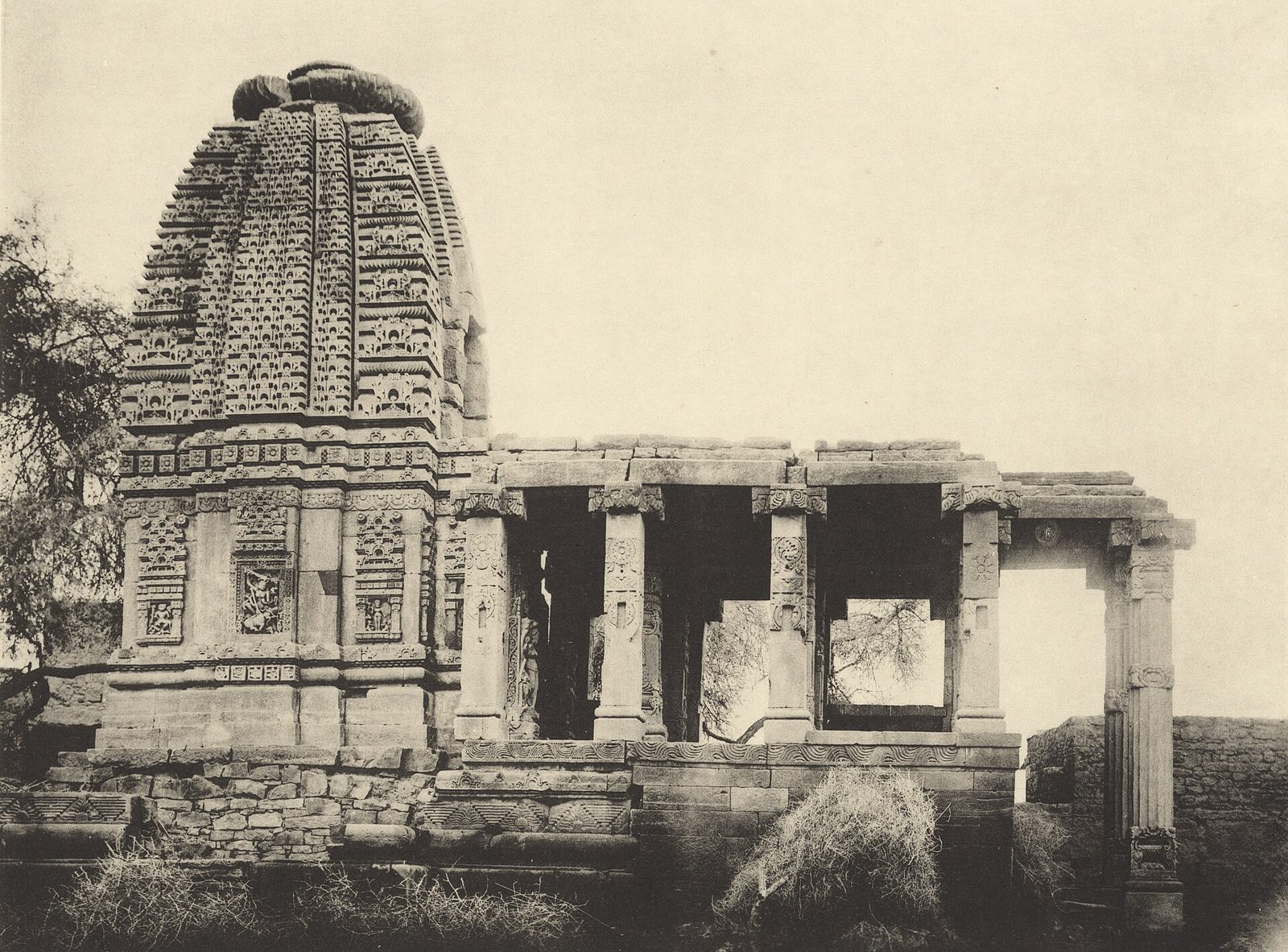 An old photograph of a small stone temple with a carved spire and an open pillared porch.