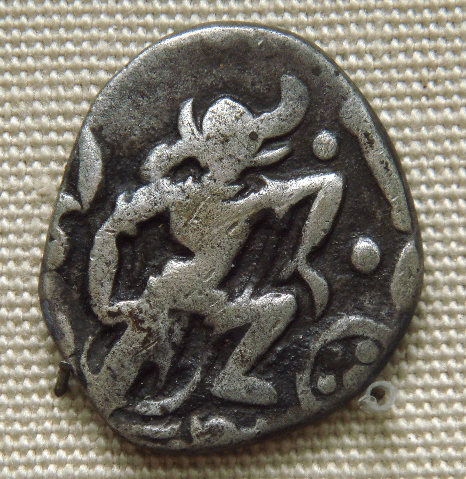 A worn silver coin with the boar-headed Varaha in a striding pose.
