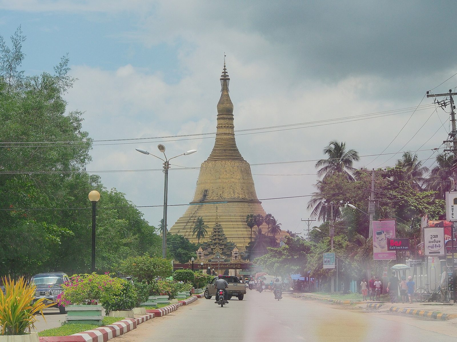 A tall gilded stupa rising above a town street.