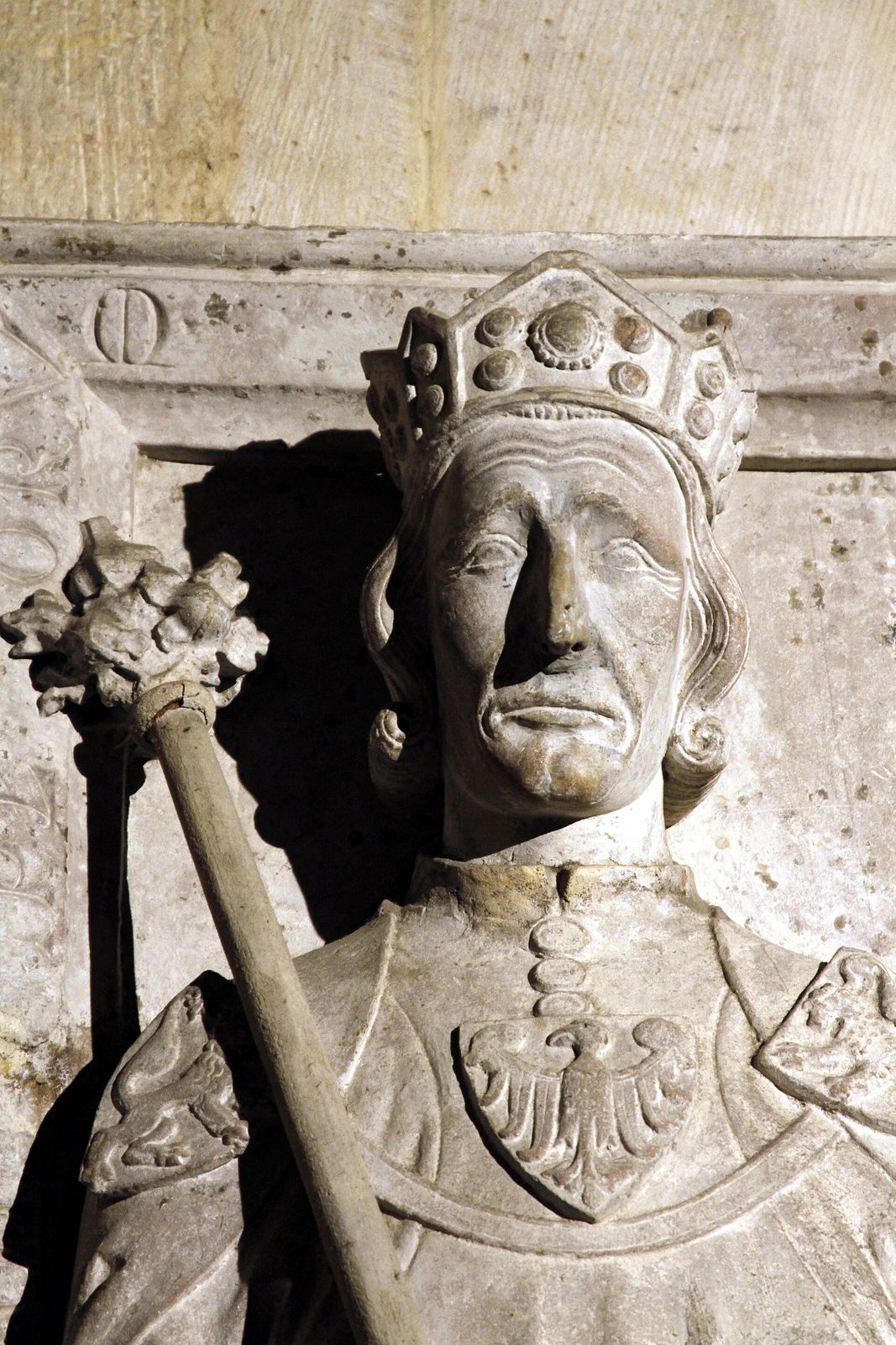 A carved stone effigy of an elderly crowned king holding a sceptre.