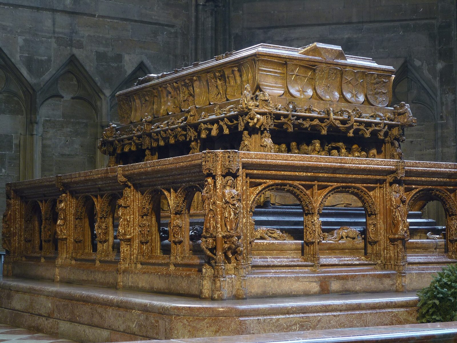 A massive red marble tomb chest with a carved effigy and an elaborate balustrade.