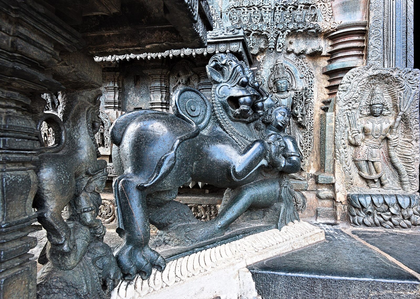 A polished stone sculpture of a man stabbing a rearing tiger-like beast.