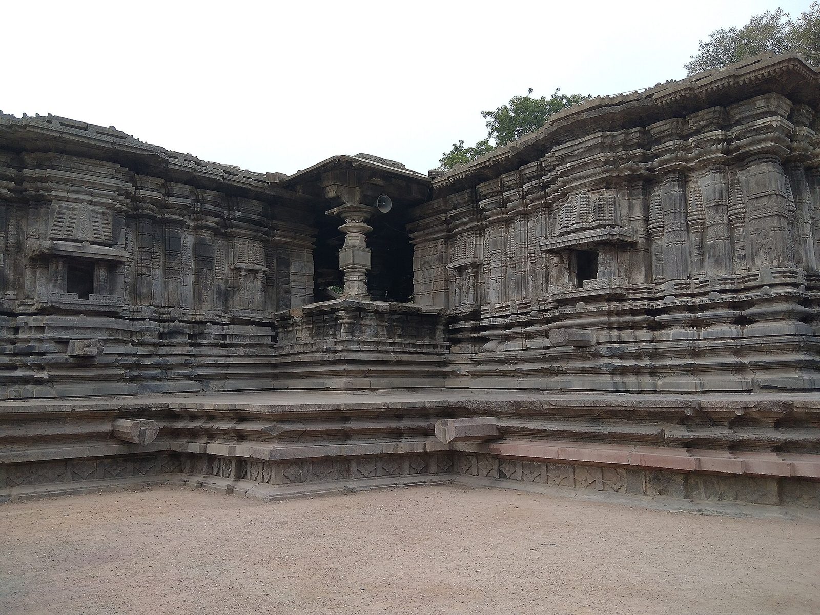 A dark stone temple with deeply carved walls and a pillared porch.
