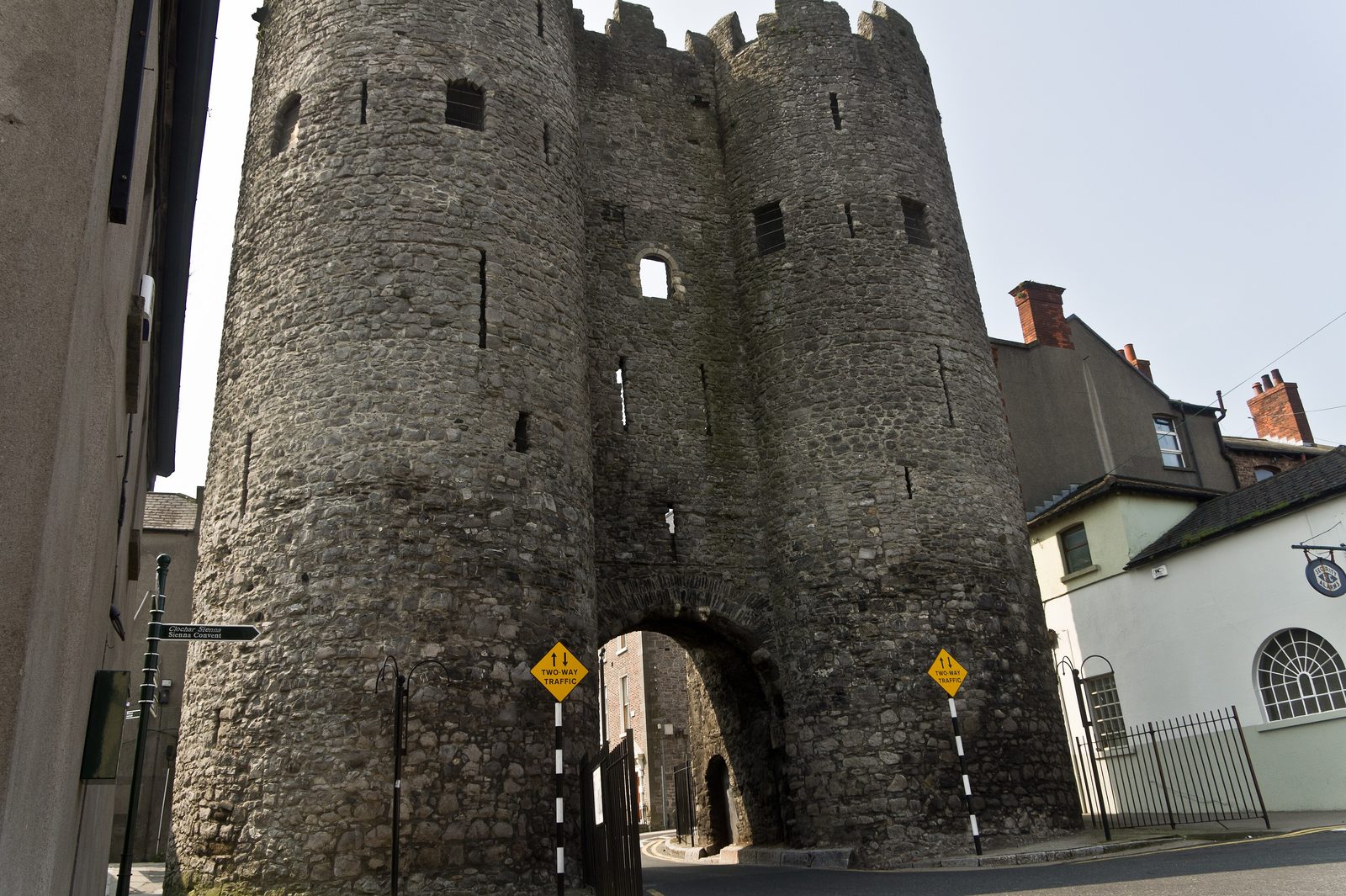 A tall twin-towered medieval stone gate over a street.