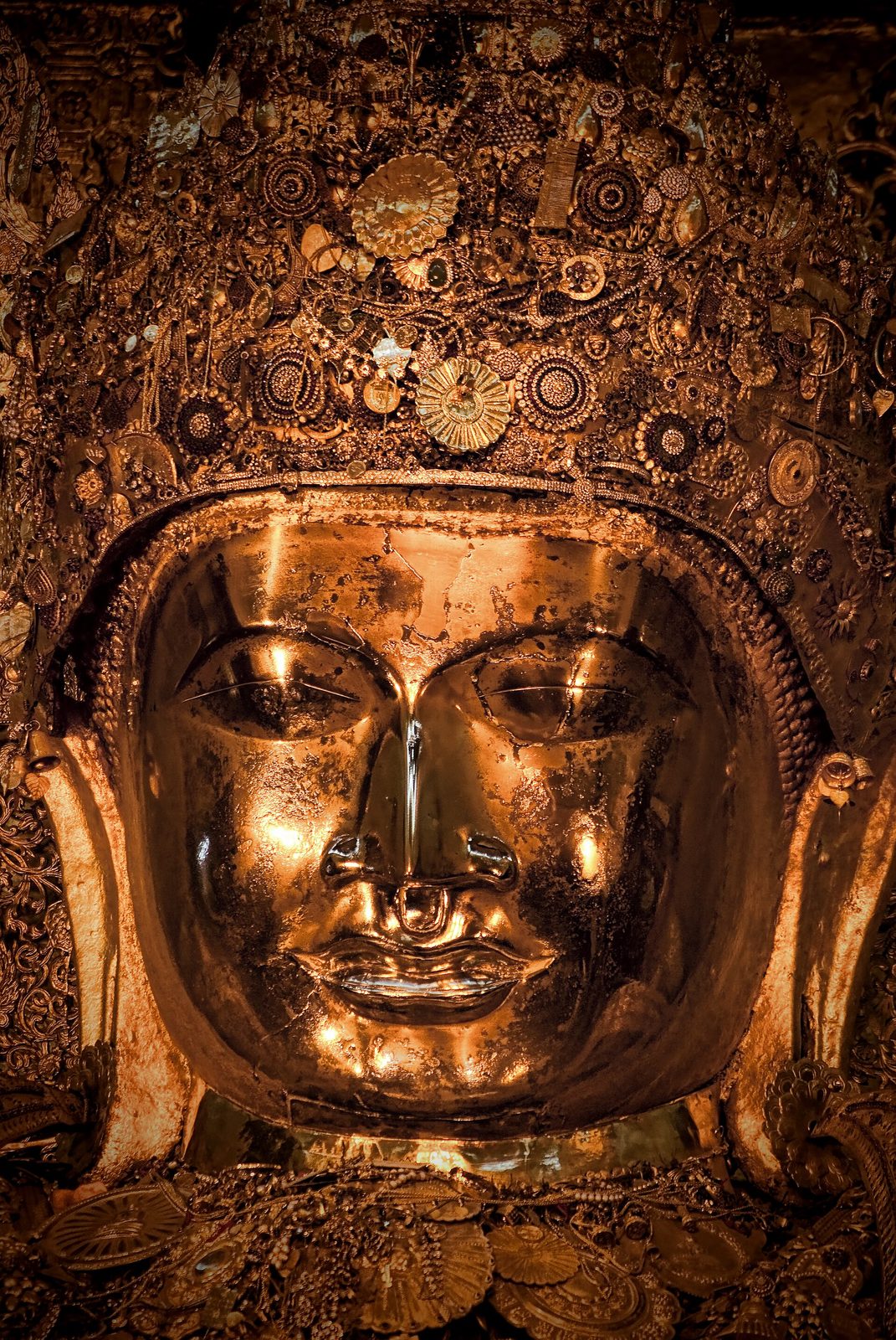 A close view of the gilded face of a Buddha image.