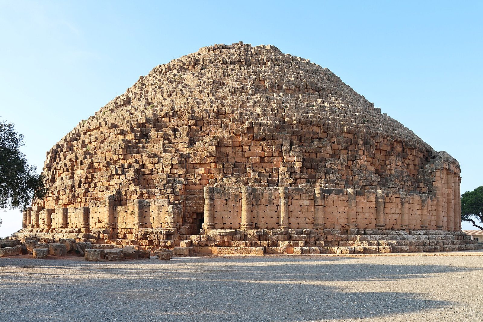 A huge round stone tomb with engaged columns around its base and a stepped cone above.