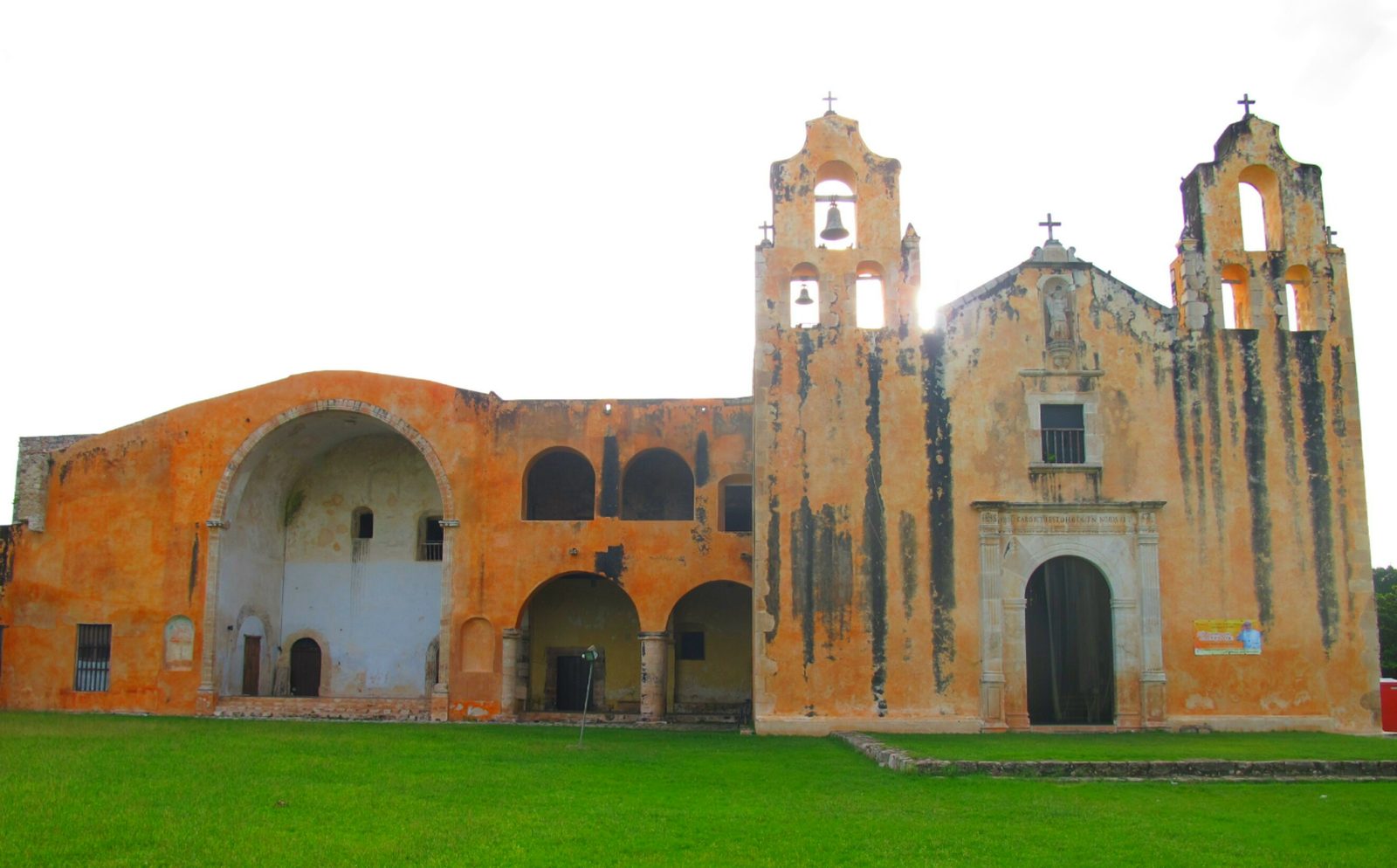A colonial church and convent with an orange front, bell gables and arcades.
