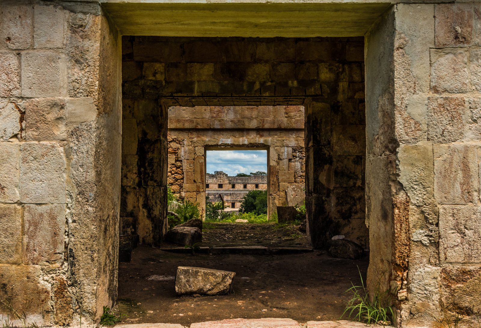 A view through a series of stone doorways toward a palace in the distance.