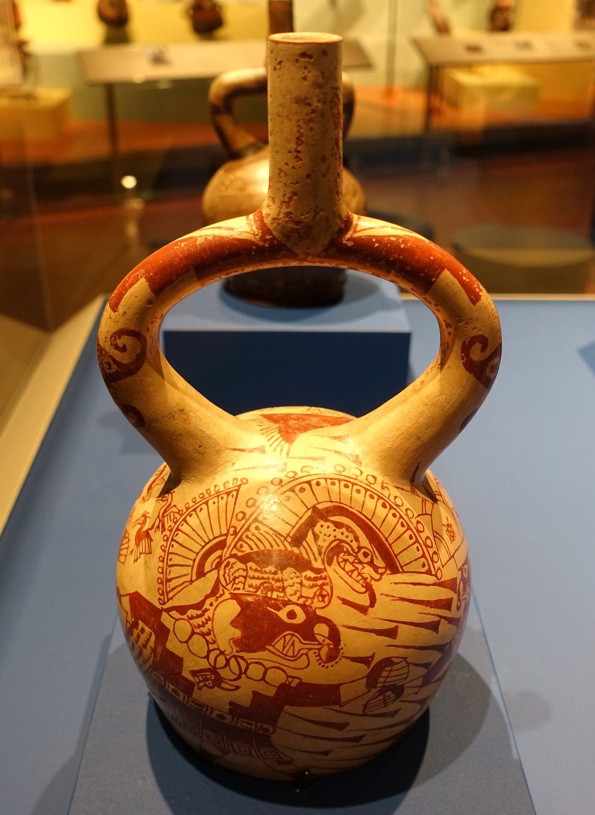 A cream ceramic stirrup-spout bottle painted in red fine line with a fighting figure.