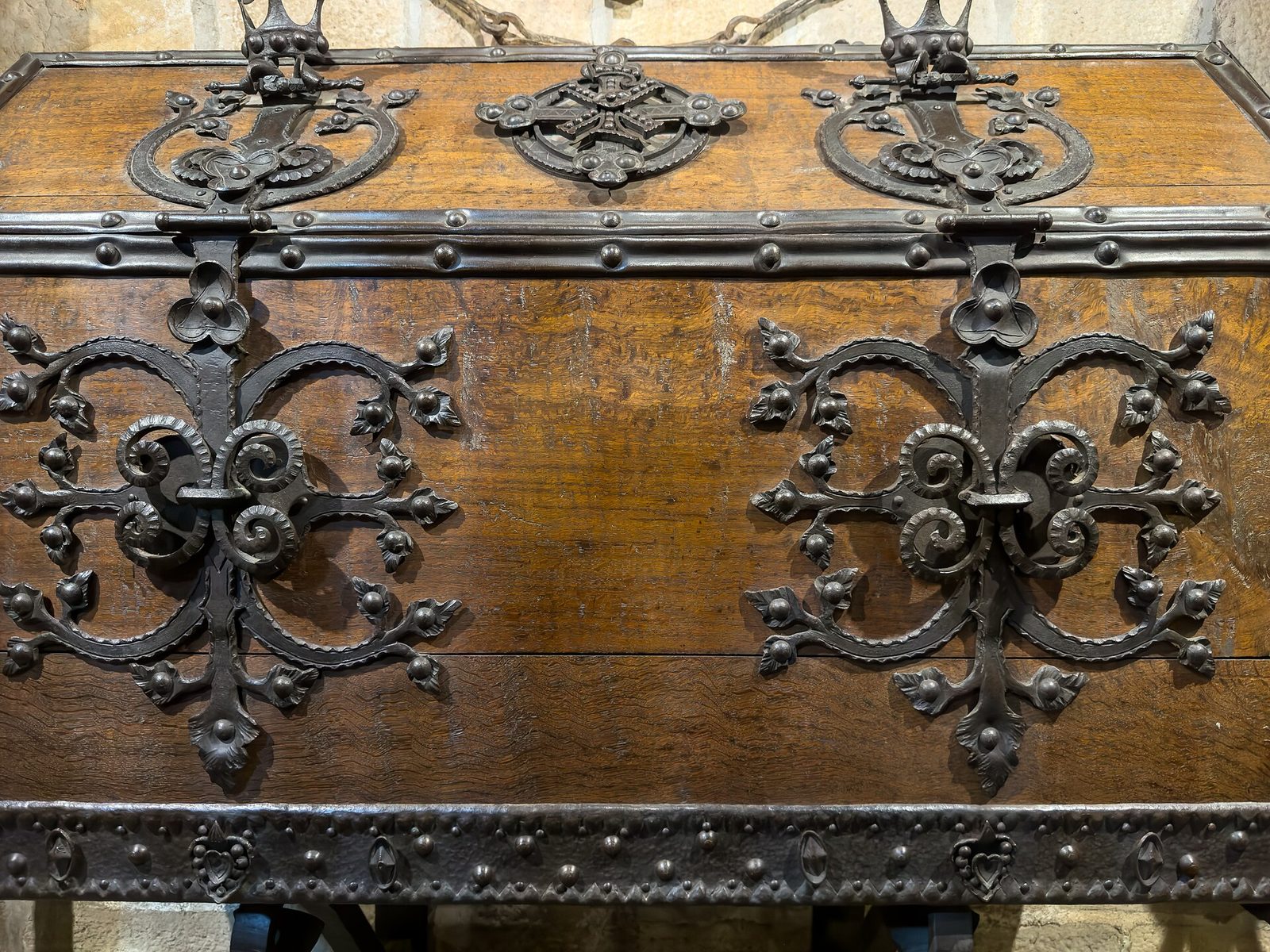A large wooden chest with elaborate wrought-iron hinges and mounts, seen close up.