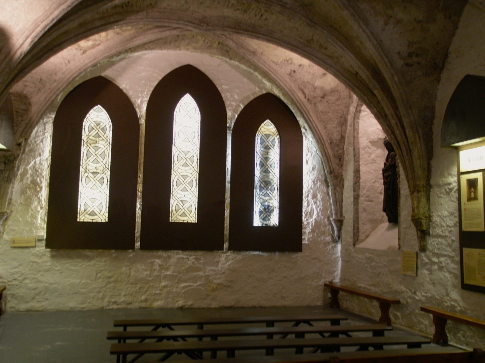 A low vaulted stone chamber with three narrow pointed windows.