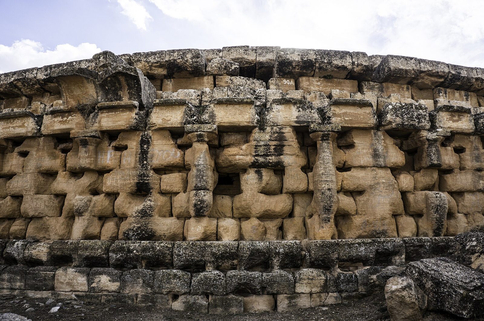A close view of the stepped stone flank of a great round tomb, ringed with engaged columns.