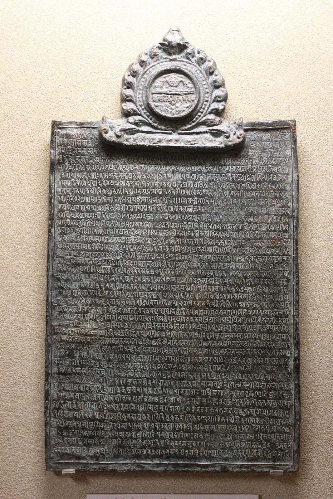 A copper plate covered in fine lines of script, with a round royal seal mounted on top.