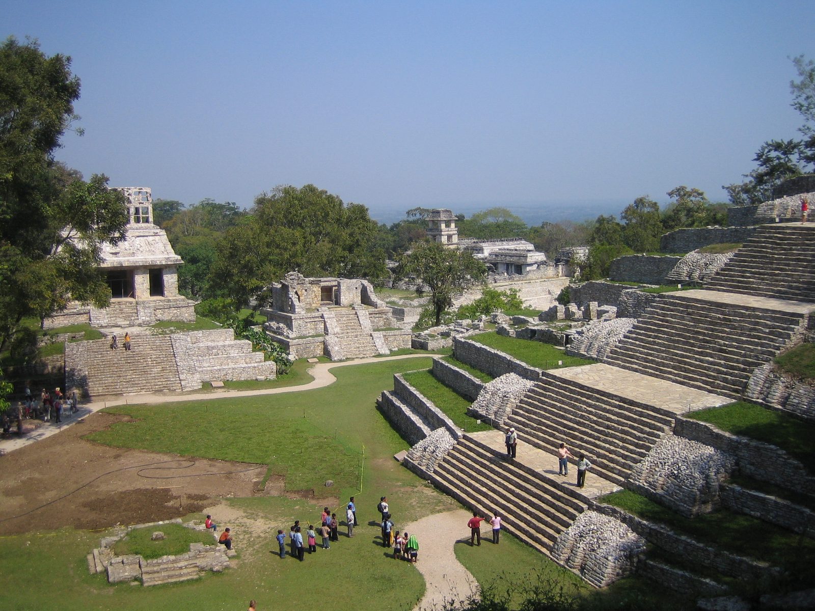 A ruined palace complex with a square tower and stairways around a grassy court, seen from above.