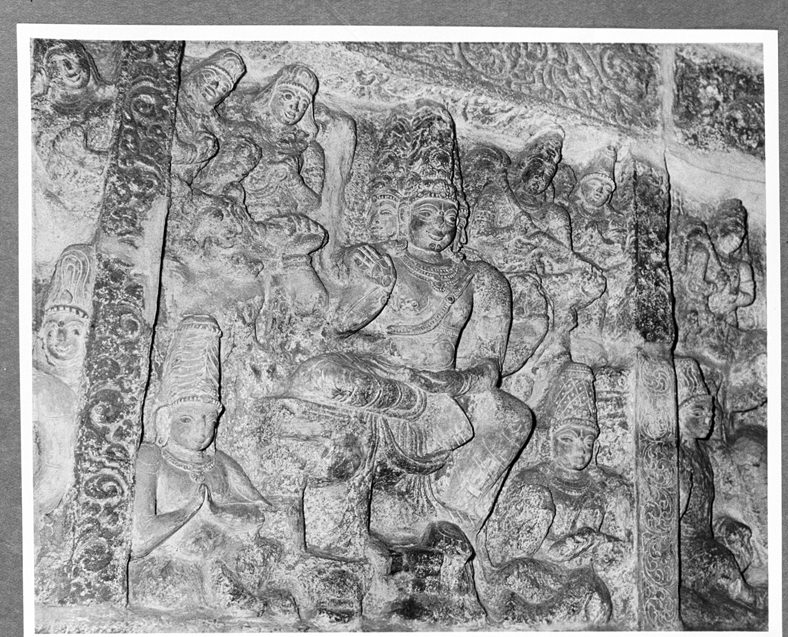 A black and white photograph of a crowded relief panel of seated and standing courtly figures.