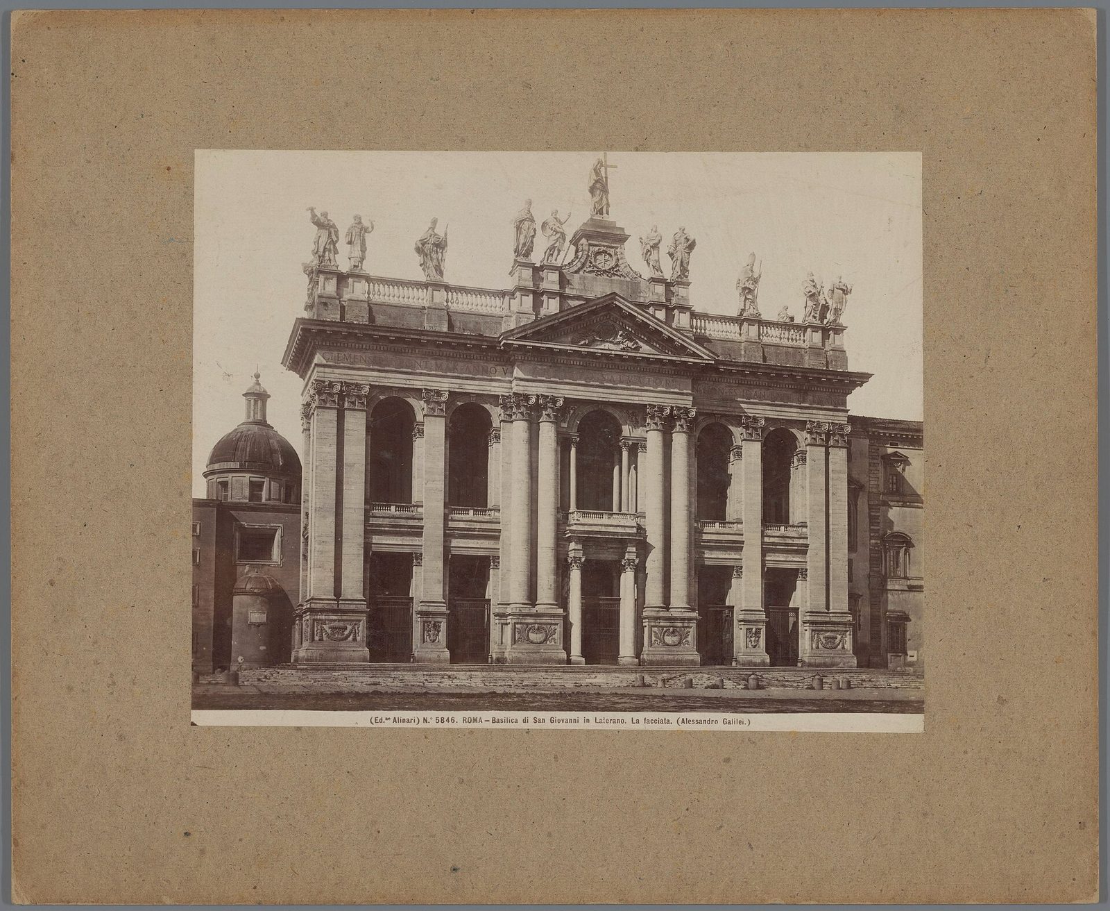 An engraved view of a great church front with a columned portico and a row of colossal statues along the roofline, seen across an open square with small figures and carriages.