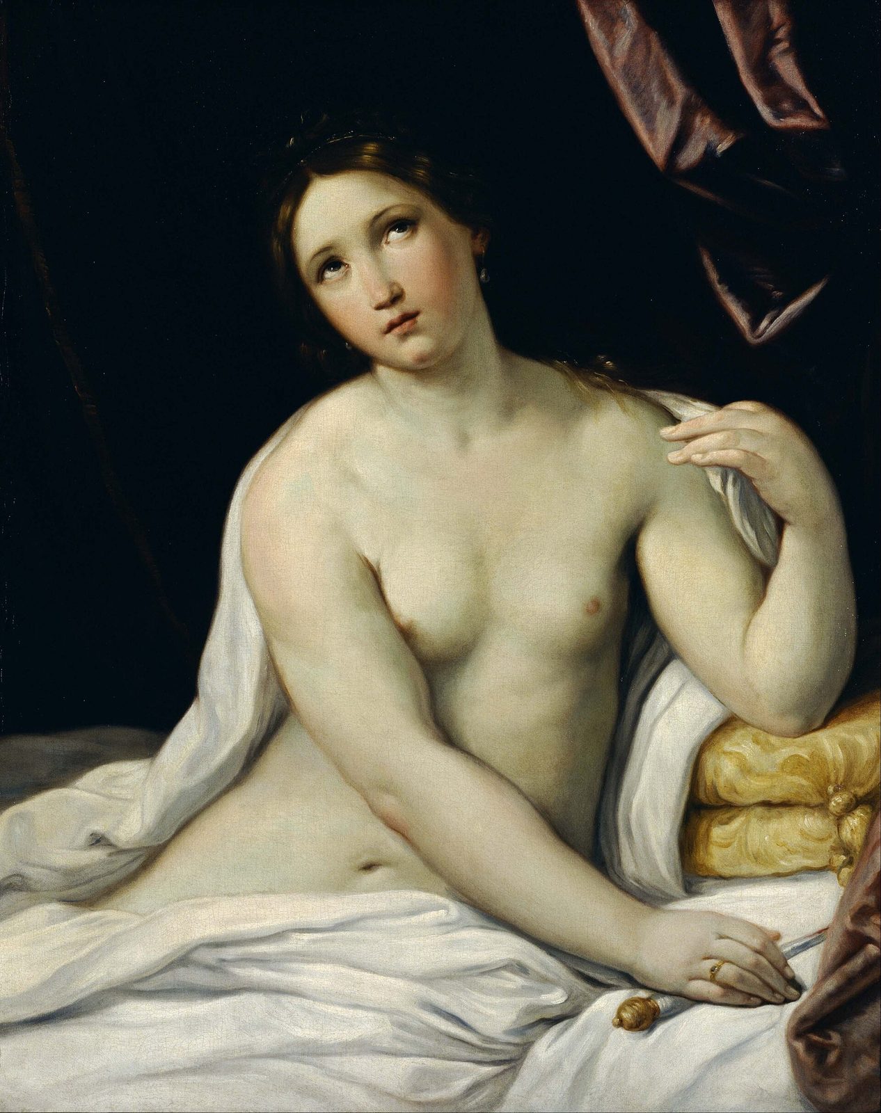 An oil painting of a woman turned half away, drapery slipping from one shoulder, her face lifted and her hand holding a short dagger against her breast, against a dark ground.