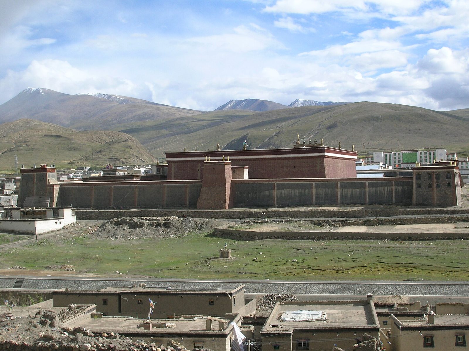 The high grey walls of a fortress-like monastery with red and white vertical stripes, under a blue sky.