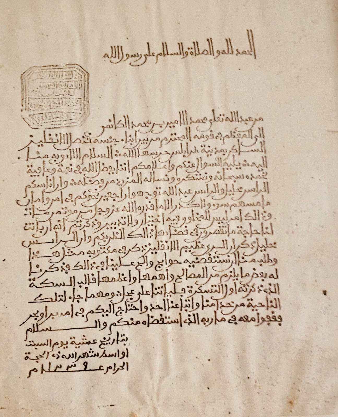 A page of Arabic handwriting in brown ink with a seal stamped at the top left.