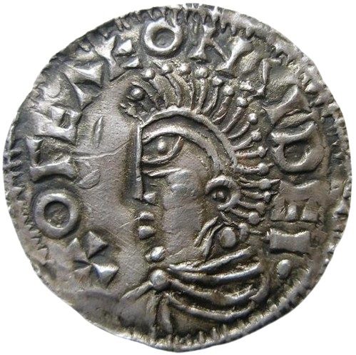 A worn silver coin showing a stylised crowned head in profile within a ring of letters.