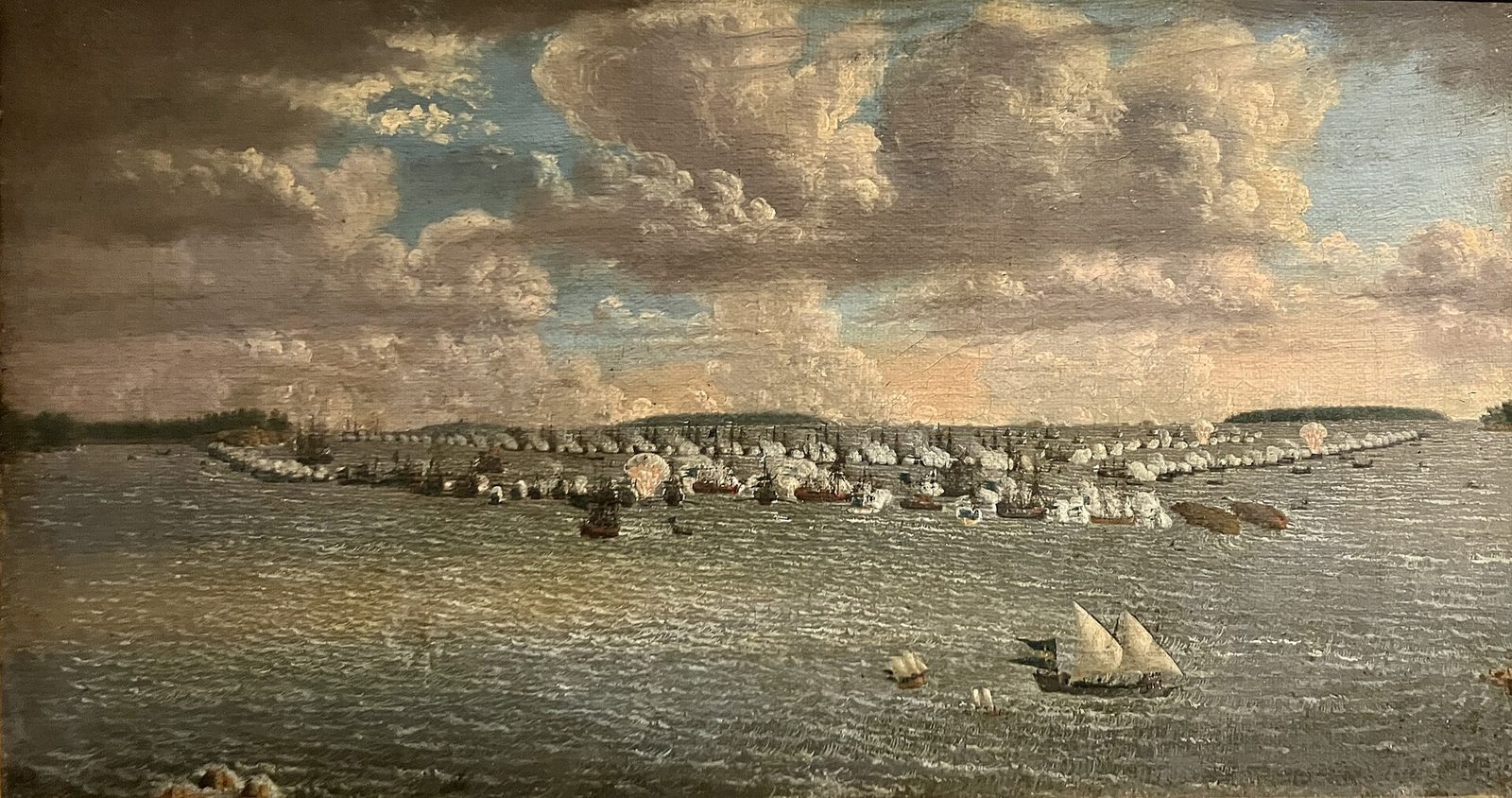 A painting of a fleet of sailing warships and galleys spread across a wide bay under a cloudy sky.
