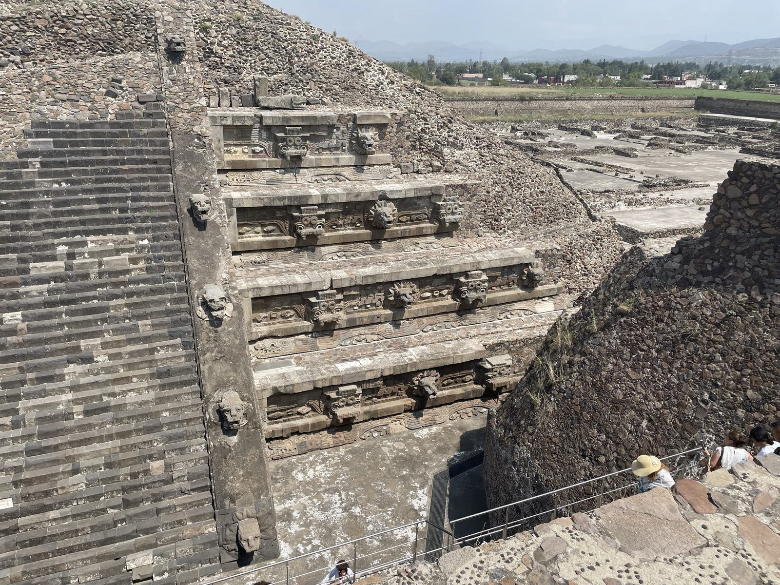 A stepped temple front with carved serpent heads, seen from the top of a later platform built against it.