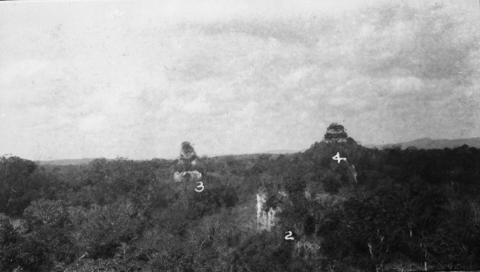 An old black-and-white photograph of temple tops rising above an unbroken forest canopy, numbered 2, 3 and 4.