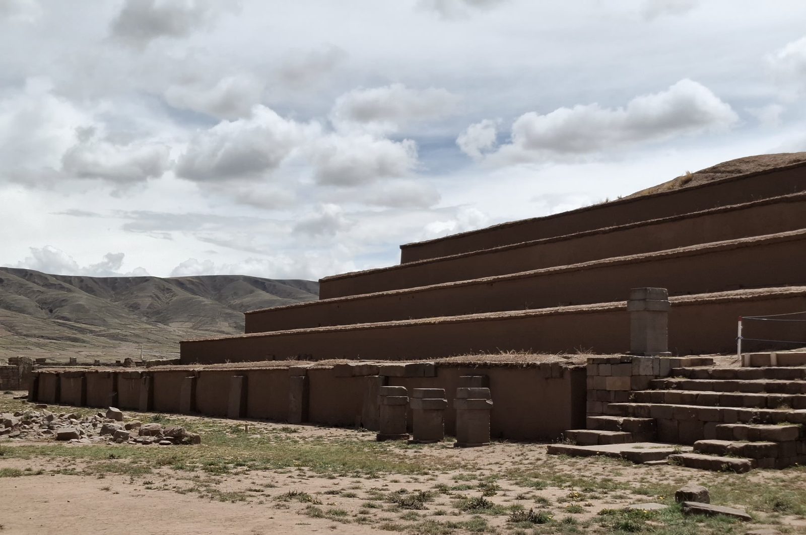 A stepped platform of low terraces faced with brown stone, under clouds.