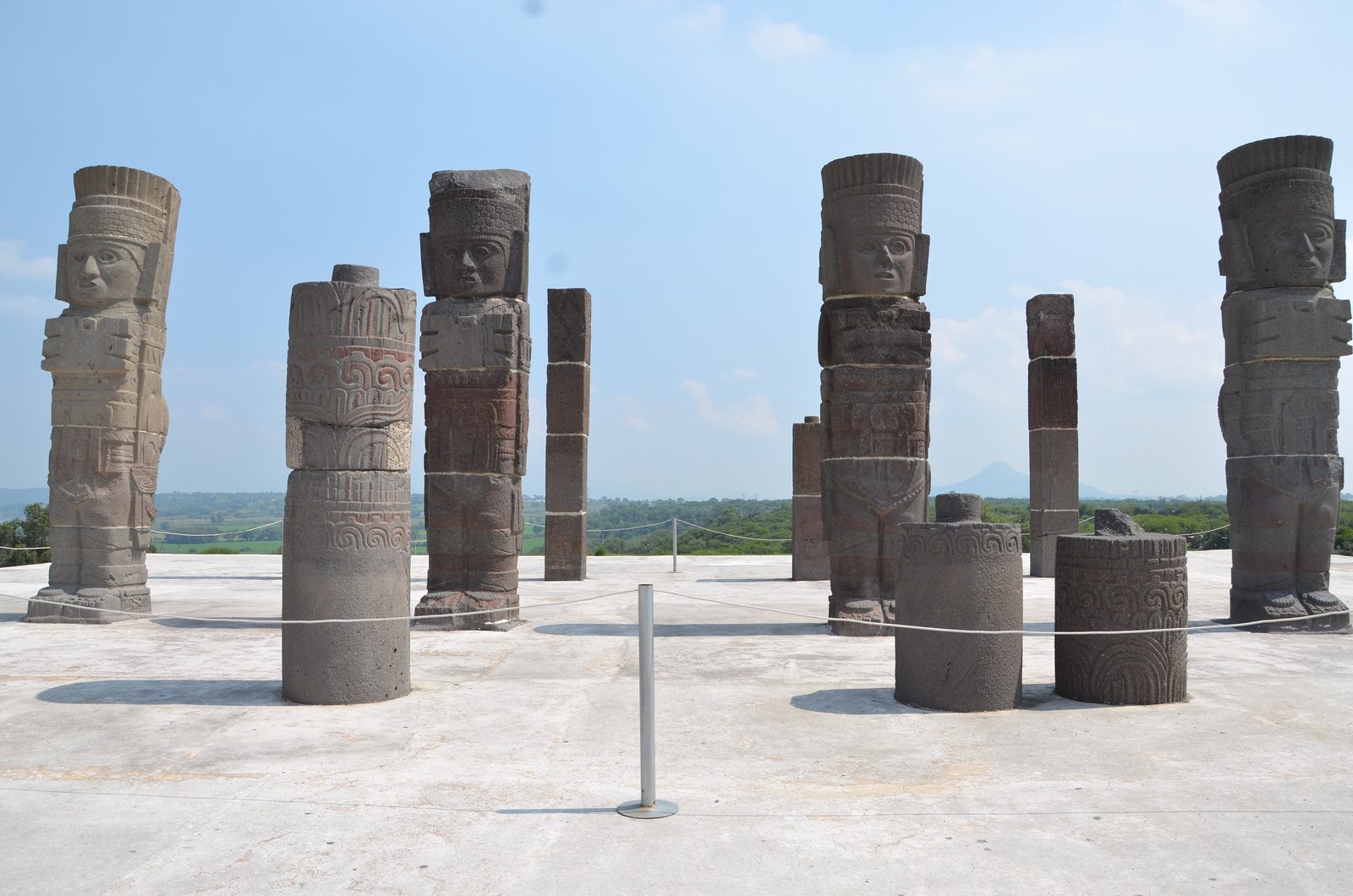 Tall stone columns carved as warriors standing on a platform.
