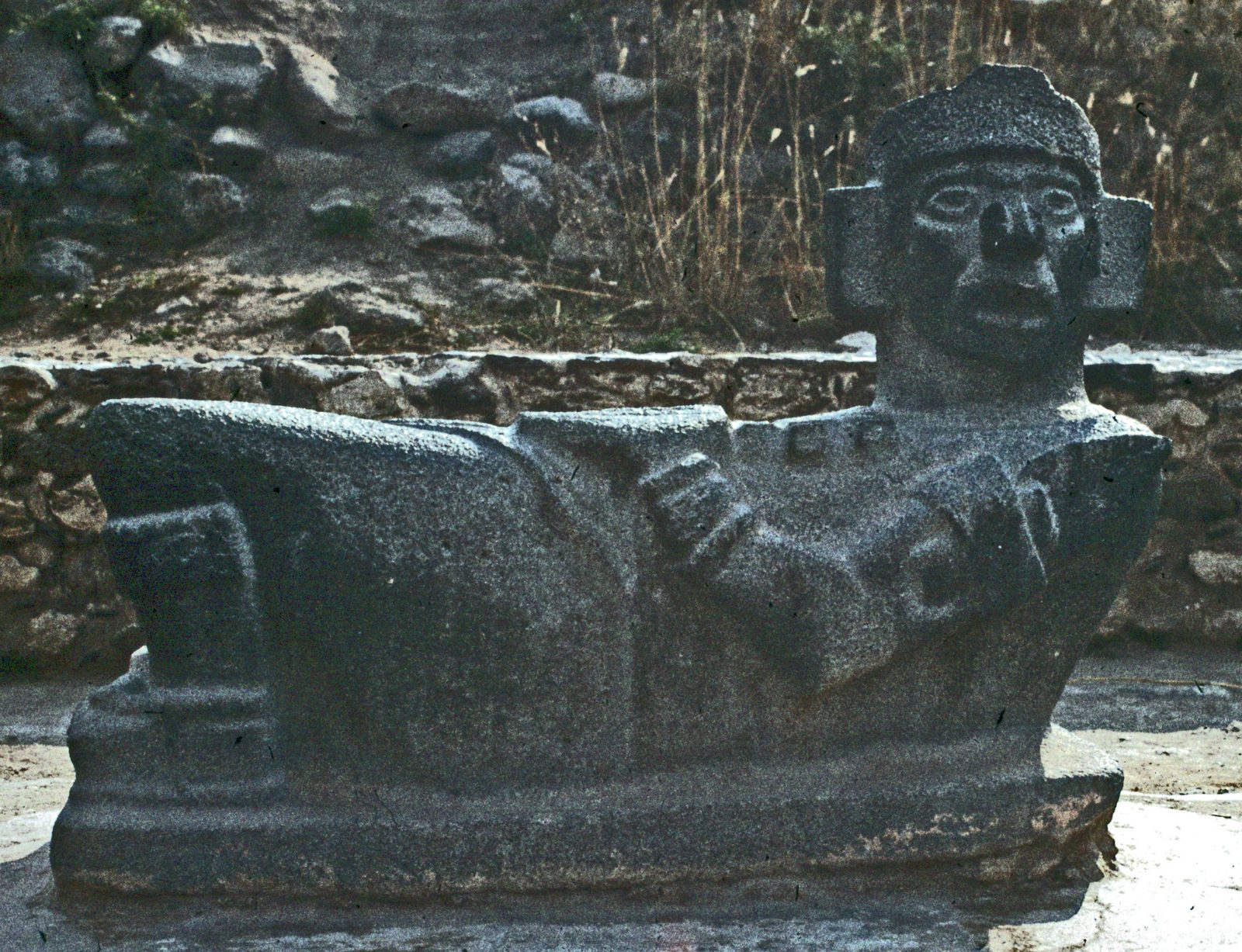 A reclining stone figure with raised knees and a turned head, holding a dish on its stomach.