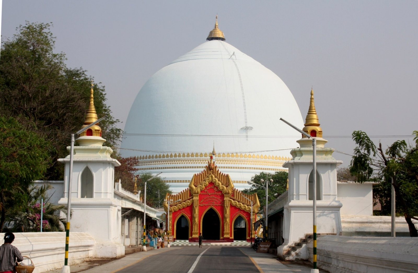 A great white dome-shaped pagoda behind a gilded gateway.