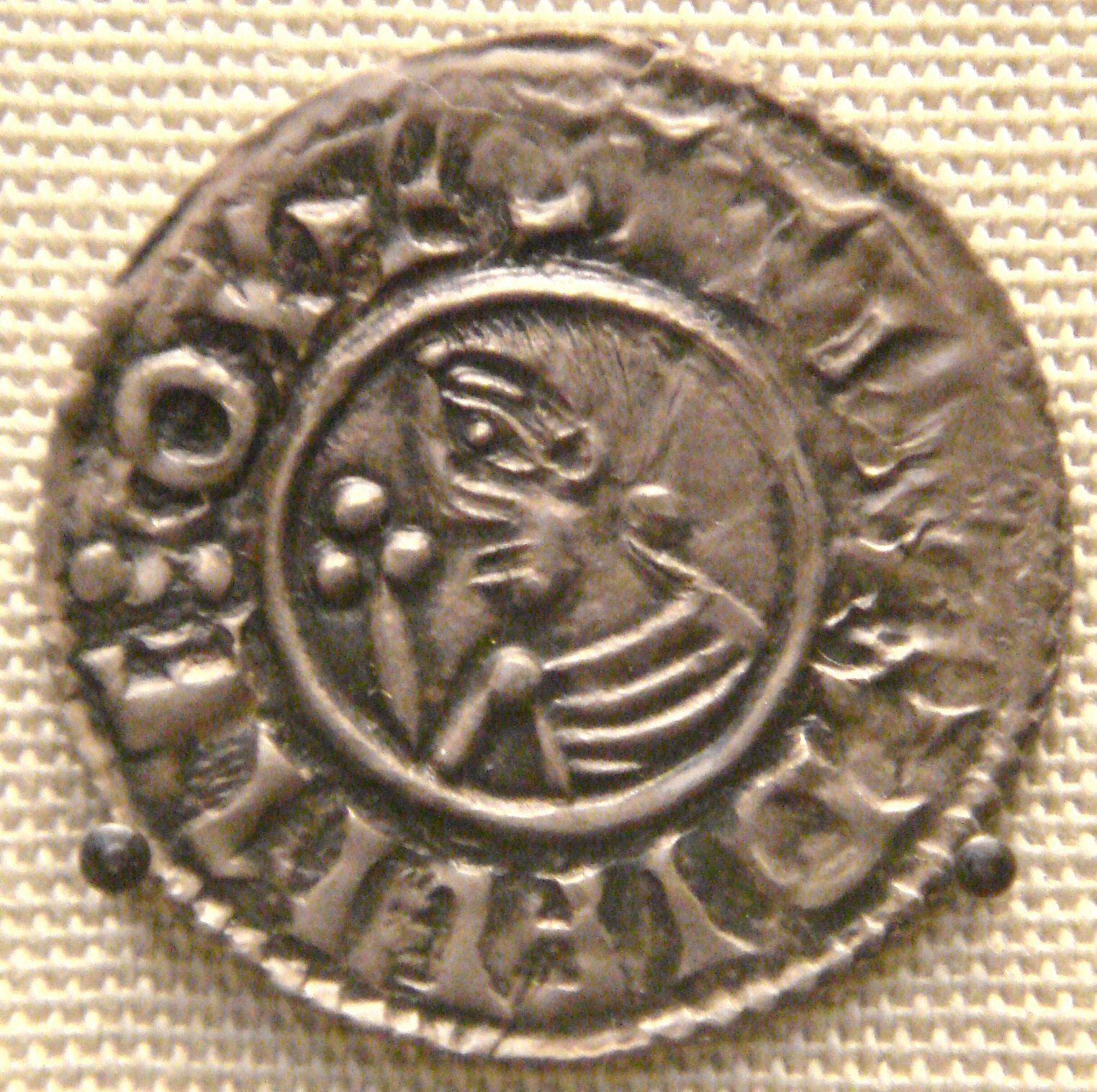 A silver penny with a profile head and a lettered border.