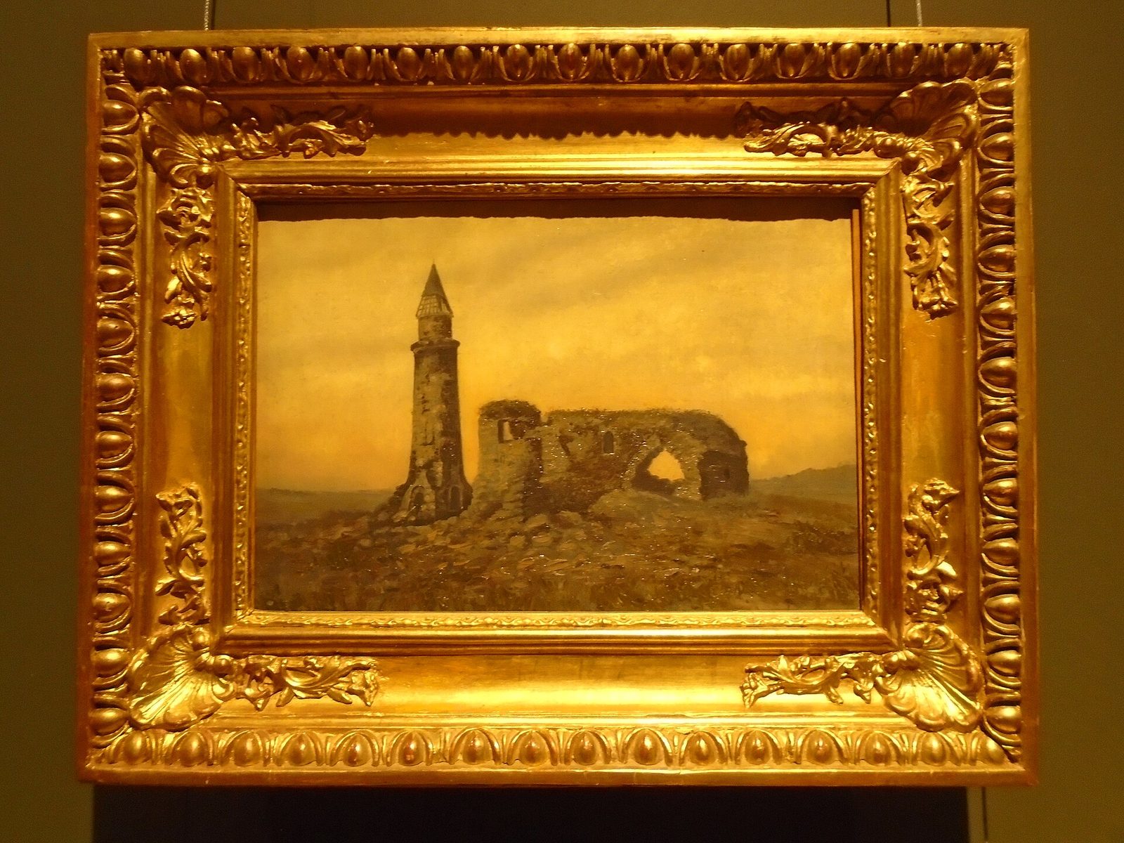 A small oil painting in a gilt frame of a ruined stone tomb and a slender minaret on an empty plain.