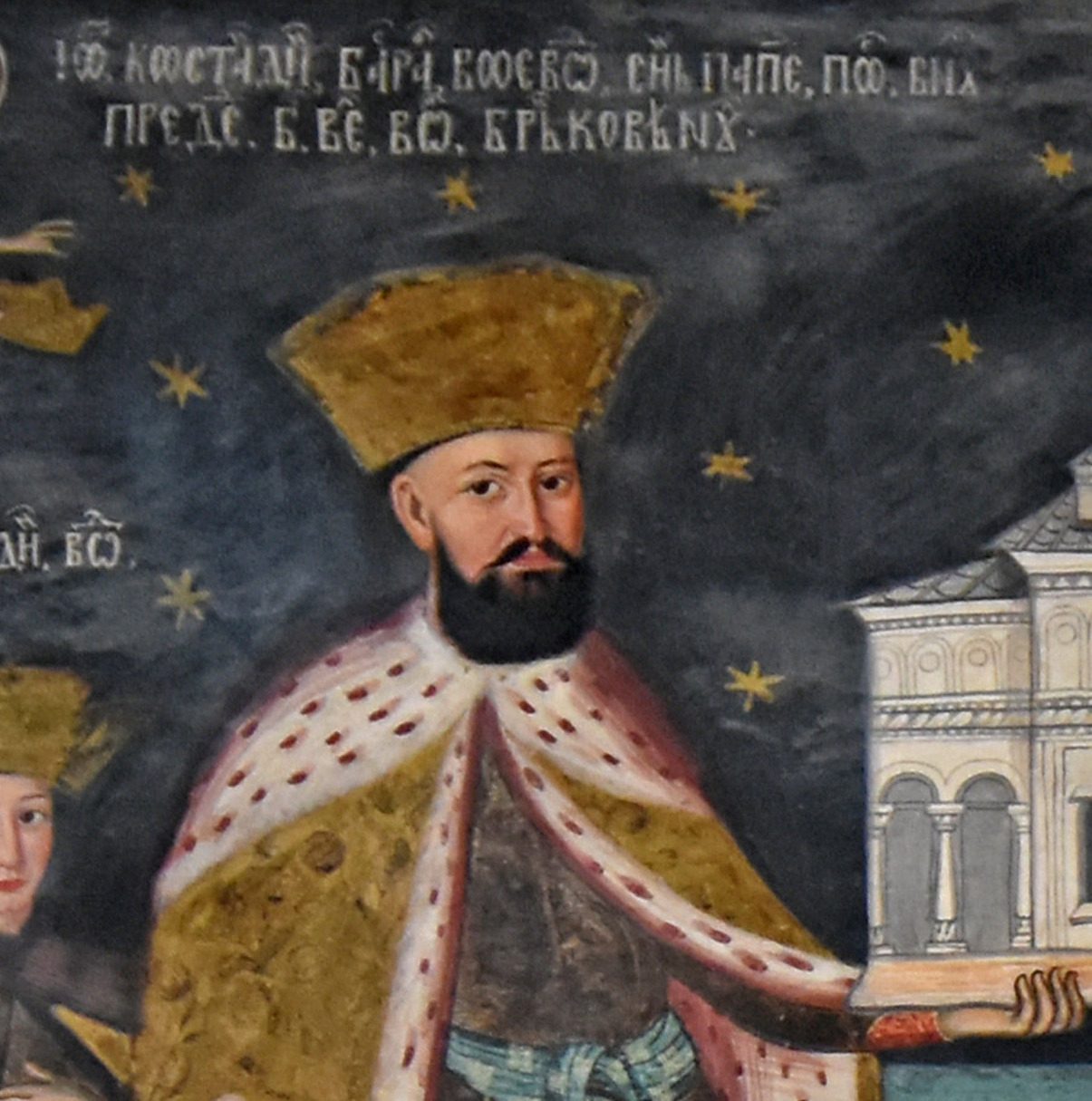A fresco of a bearded prince in a fur-trimmed robe and gold cap, holding a model church, under a band of Cyrillic.