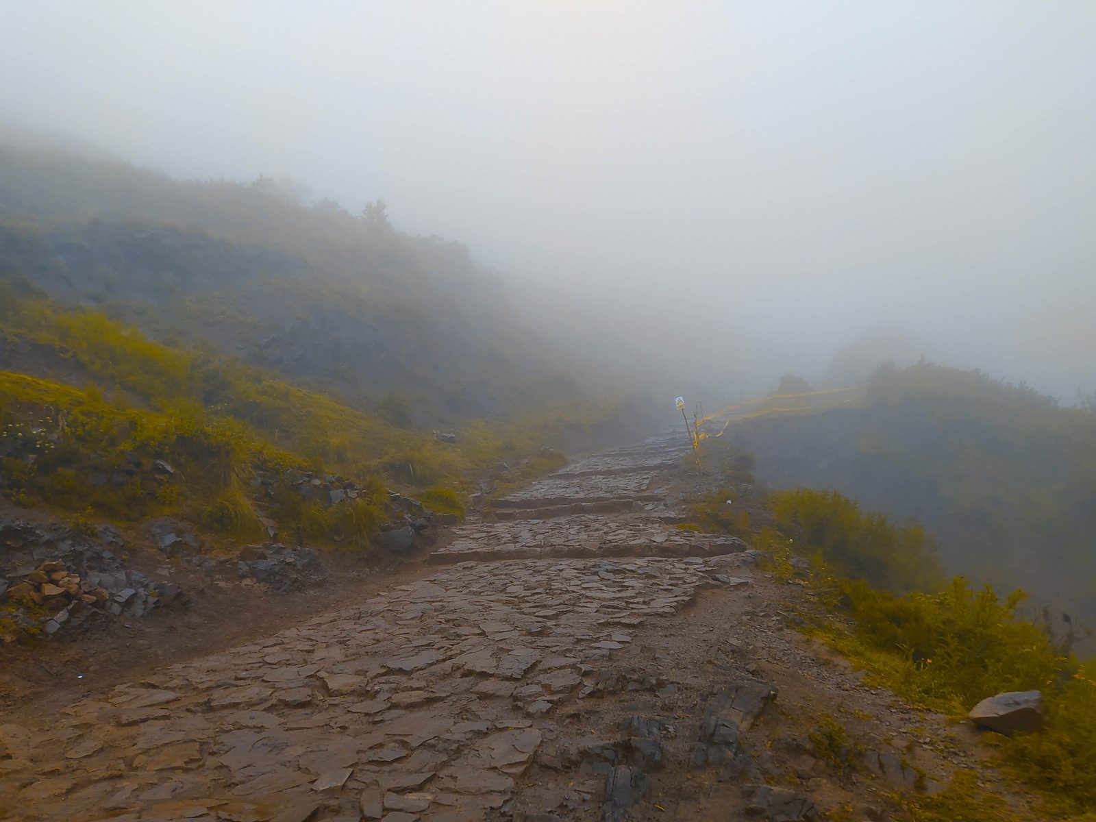 A paved stone path running along a hillside into mist.